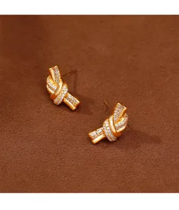 Close-up of gold-plated knot stud earrings with shimmering pave zircon details