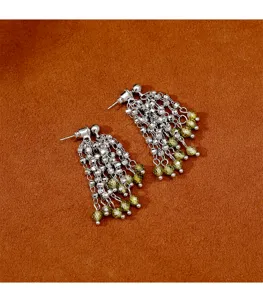 Primer plano de pendientes de borla de plata con cuentas de cristal facetado verde.