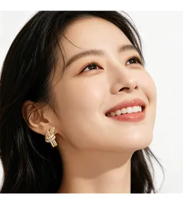 Detailed view of an Asian model wearing golden knot stud earrings with sparkling diamonds.