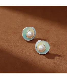 Primer plano de elegantes pendientes de perlas con esmalte degradado y diseño en espiral