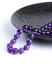 Macro view of natural deep purple amethyst round beads on a textured black plate