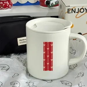 White ceramic coffee mug with lid and spoon, cute bow pattern, ideal for office and home use.