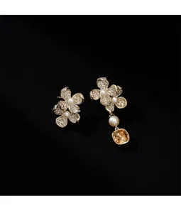 Detalle de pendientes de flores asimétricos con perlas blancas y piedra preciosa amarilla