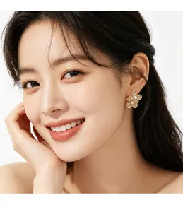 Primer plano de una modelo luciendo un elegante pendiente floral dorado con perlas.