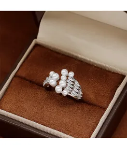 Detailed close-up of an elegant pearl and baguette zircon ring in a luxury brown gift box