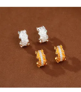 Detalle de pendientes en forma de C plisados de diseño con circonitas blancas brillantes.