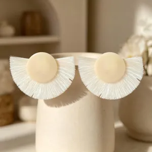 Vue de détail d'élégantes boucles d'oreilles à franges blanc cassé au design minimaliste chic.
