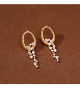 Primer plano de pendientes dorados estilo cascada con brillantes circonitas transparentes