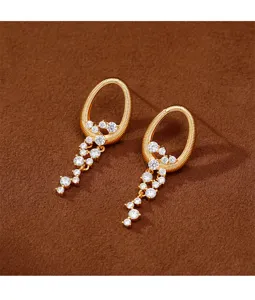 Detalle de pendientes de oro con cascadas de circonitas brillantes en forma de estrella