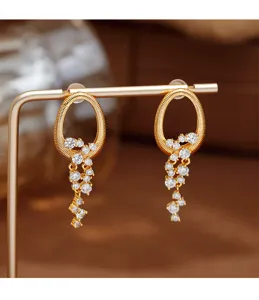 Detalle de pendientes de lujo chapados en oro con bellas piedras de circón en cascada