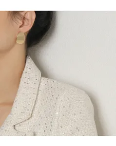 Gros plan d'une boucle d'oreille géométrique minimaliste en or portée par un mannequin
