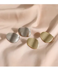 Gros plan sur des boucles d'oreilles clous géométriques en métal doré et argenté