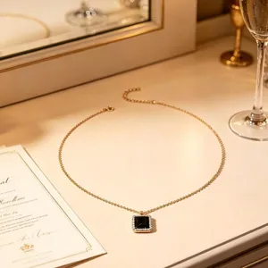 Detailansicht einer goldenen Kette mit einem quadratischen schwarzen Stein Anhanger und Strass.