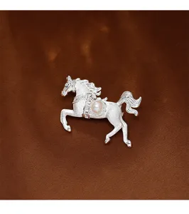 Macro detail of elegant silver brushed horse brooch with pearl and crystal accents.