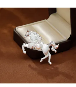 Detail shot of a brushed silver horse brooch featuring a pearl and rhinestone inlay