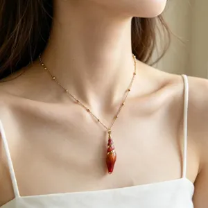 Detail view of summer resort style conch shell pendant necklace, elegant gold chain jewelry.