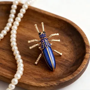 Elegante blauwe kever broche met sprankelende blauwe strass steentjes en parel details.