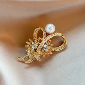 Exquisite detail close-up of a golden rhinestone flower brooch with a glossy pearl accent.