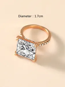 Nahaufnahme eines roségoldenen Ringes mit quadratischem Zirkoniastein und glitzernden Seitensteinen.