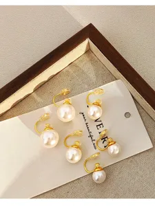 Close-up detail of retro white pearl clip-on earrings with gold mosquito coil design