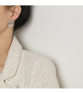 Gros plan d'une élégante boucle d'oreille géométrique en argent portée par un modèle