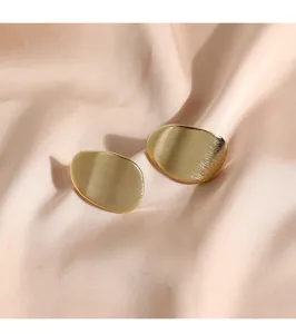 Gros plan de boucles d'oreilles géométriques minimalistes en or à texture brossée.