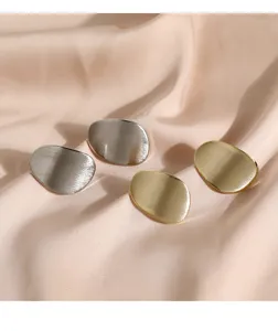 Gros plan de boucles d'oreilles puces géométriques minimalistes en or et argent mat