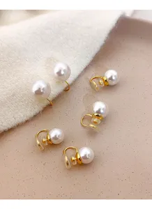 Close-up of elegant gold clip-on earrings with large white pearls on soft background