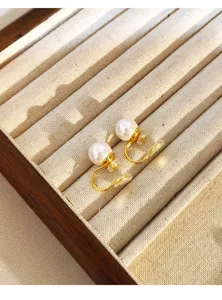 Detail of vintage pearl clip-on earrings with mosquito coil design on a jewelry tray.