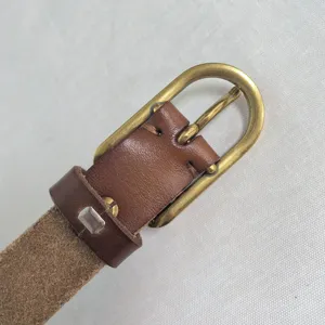 Detail shot of a brown leather belt with a vintage gold-toned metal pin buckle and loop.
