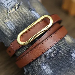 Close-up detail of a brown thin genuine leather women belt with golden oval metal buckle.