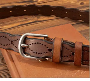Close-up detail of vintage genuine leather women belt with hollow carved pattern and pin buckle.