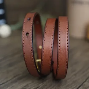 Slim brown leather belt for women, minimalist vintage waist strap with fine stitching details.