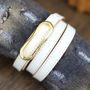 White thin leather belt detail shot with gold metal buckle, stylish minimalist design accessory.