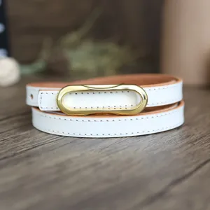 Close-up of a white leather belt with a sleek gold-tone oval buckle, elegant minimalist design.