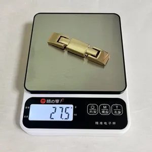 Detail view of the golden metal belt buckle weighing 27.5g on a scale, premium hardware accessory.
