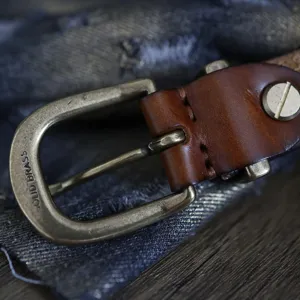 Primo piano della fibbia in ottone vintage e dettagli della lavorazione in vera pelle.