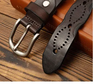 Close-up detail of vintage genuine leather women belt with antique metal buckle and cutout pattern.