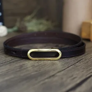 Detailed close-up view of dark brown leather belt featuring elegant gold-tone oval buckle.