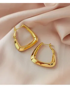 Gedetailleerde weergave van minimalistische gouden geometrische oorringen op roze satijn