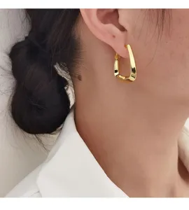 Detailopname van een minimalistische gouden geometrische oorring op een model