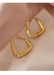 Detailopname van minimalistische gouden geometrische oorbellen op roze zijde