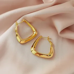 Minimalistische geometrische gouden oorringen voor dames op elegante roze zijden stof