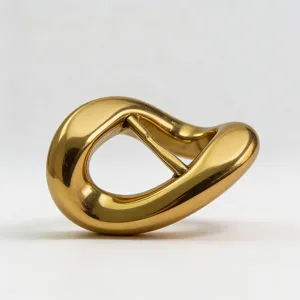 Close up detail of irregular gold metal belt buckle accessory, smooth glossy surface finish.