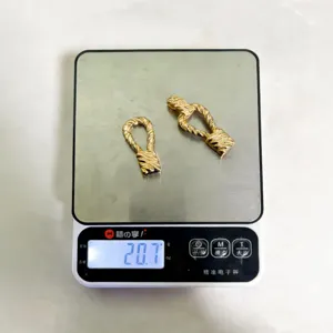 Detailed shot of gold twisted metal apparel belt buckle accessories displayed on scale.