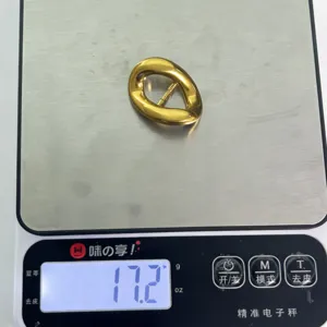 Close-up detail of irregular gold metal belt buckle accessory, weight display on electronic scale.