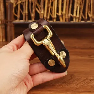 Close-up detail of genuine leather belt key holder with solid brass hook and rivet accessories.