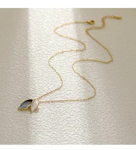Detailed view of a gold-toned leaf necklace with grey and white enamel pendants