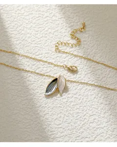 Close-up detail of gold leaf-shaped pendant necklace with colorful enamel finish