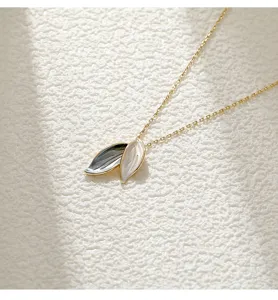 Detail view of elegant dual-leaf pendant necklace with white and grey enamel finish